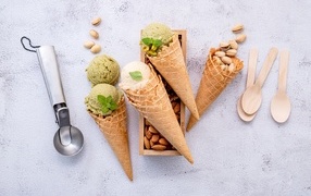 Фисташковое и сливочное мороженое с рожками на столе 