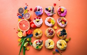 Sweet donuts on an orange background with fruits and flowers