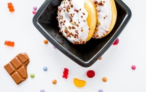 Два пончика в тарелке на белом фоне с конфетами