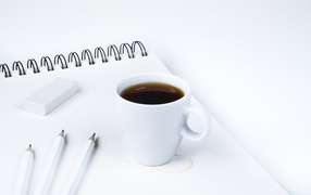 A cup of aromatic coffee with a notepad on the table