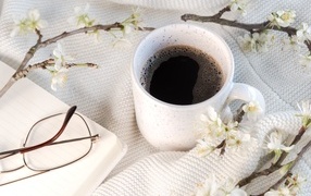 A cup of coffee with a flowering branch on the table