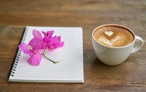 Cup of coffee on the table with notepad and flowers