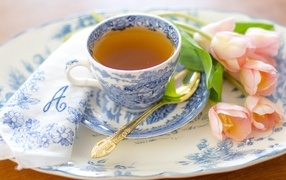 Cup of tea on a plate with pink tulips