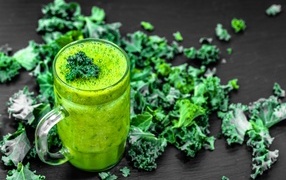 Glass with green smoothie with leaves