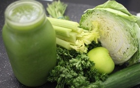 Healthy green smoothie on the table with vegetables and herbs