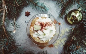 Hot coffee with whipped cream in a cup on a table with fir branches