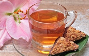 Чай на столе с розовой лилией и конфетами