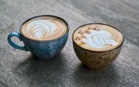 Two cups of coffee with a pattern on the foam