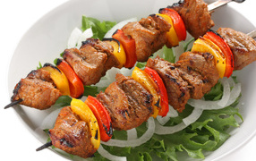 Appetizing kebab with peppers and onions on a plate with lettuce