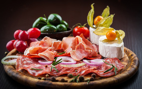 Board with sliced ham, vegetables and cheese