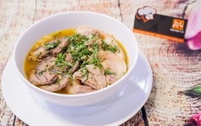 Broth with meat in a white plate on the table