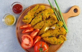 Fried chicken with tomatoes and green onions on the board