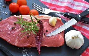 Large piece of pork on the table with garlic and tomatoes