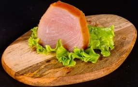 Piece of meat with a lettuce leaf on a cutting board