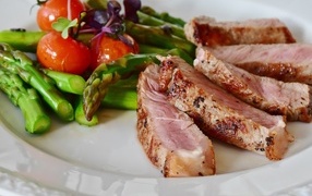 Pieces of appetizing meat on a plate with asparagus