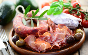 Колбаса, ветчина и оливки на деревянной тарелке