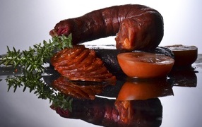 Sausage with tomatoes on a mirror table