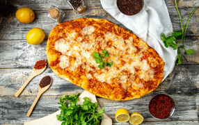 Pizza on the table with lemons and spices