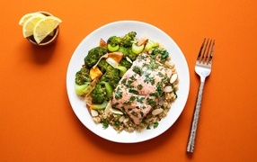 Вкусная рыба на тарелке с овощами и кашей