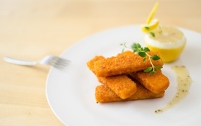 Fried fish fingers on a plate with lemon