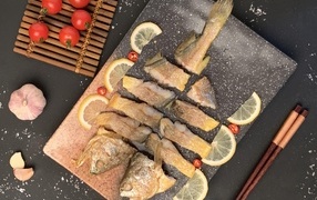 Fried fish on the table with tomatoes and lemon