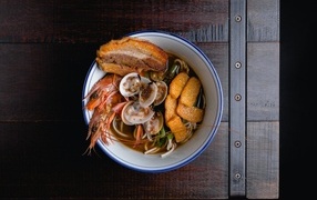 Noodle soup with seafood on wooden table