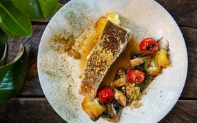 Кусок запеченной рыбы на тарелке с овощами