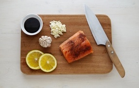 Piece of red fish on a board with lemon and garlic
