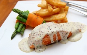 Red fish in sauce on a plate with french fries