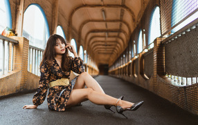 Девушка в красивом коротком платье сидит на полу