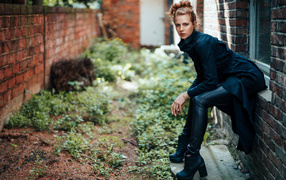 Девушка в черном наряде сидит на окне