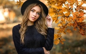 Девушка в черной шляпе стоит у дуба