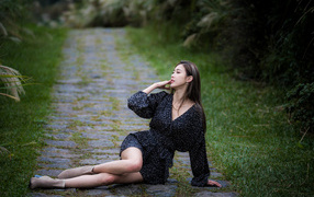 Девушка азиатка в платье лежит на дороге в парке