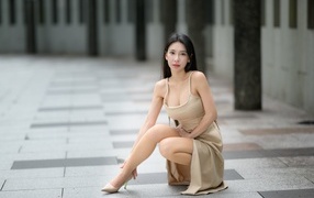 Девушка азиатка в платье сидит на корточках