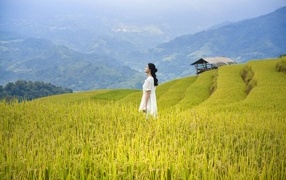 Девушка азиатка в белом платье дышит горным воздухом