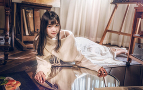 Девушка азиатка в белом платье лежит на полу