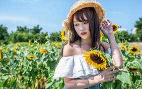 Девушка азиатка на поле с подсолнухами