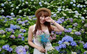 Девушка азиатка у куста с цветами гортензии