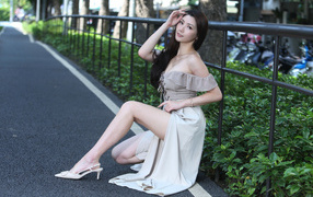 Девушка азиатка сидит у забора