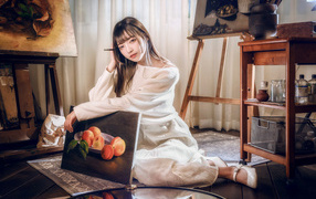 Девушка азиатка сидит с картиной на полу