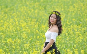 Девушка азиатка стоит на рапсовом поле