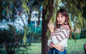 Девушка азиатка стоит у дерева ели