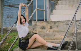 Девушка азиатка потягивается на ступеньках