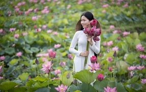 Девушка азиатка с розовыми цветами лотоса в руках