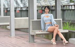 Beautiful dark-haired Asian girl sitting on a bench
