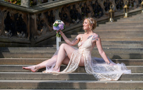 Красивая девушка невеста в платье с букетом на ступеньках