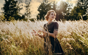 Красивая девушка в черном платье на поле с колосьями