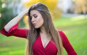 Красивая девушка в красном платье с рукой в волосах