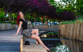 Красивая девушка опустила ноги в воду