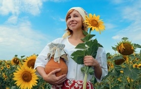 Красивая девушка с кувшином на поле с подсолнухами